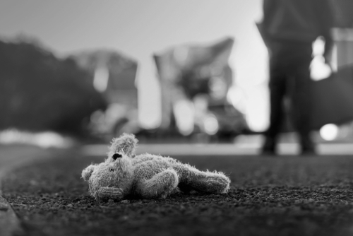 Tampa kidnapping lawyer illustrated through an abandoned teddy bear on the pavement with a distant adult figure, reflecting the severity of kidnapping accusations.