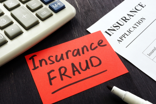 Tampa insurance fraud lawyer represented through a red note reading Insurance Fraud beside a calculator and insurance paperwork, symbolizing allegations of fraudulent claims.