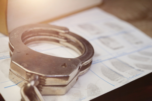 Handcuffs resting on a fingerprint form, symbolizing criminal booking procedures and the legal defense provided by a Tampa felony charges defense lawyer.