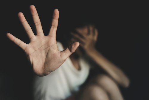A person extending an open hand toward the camera while covering their face, symbolizing sensitive allegations addressed by a Tampa rape defense lawyer.
