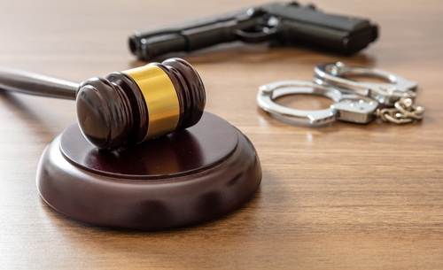 Judge’s gavel with handcuffs and a firearm on a table, representing serious homicide cases handled by a Tampa murder defense attorney.