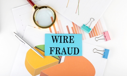Charts, graphs, a magnifying glass, and a blue card labeled Wire Fraud arranged on a desk, representing financial investigations handled by a Tampa wire fraud criminal lawyer.