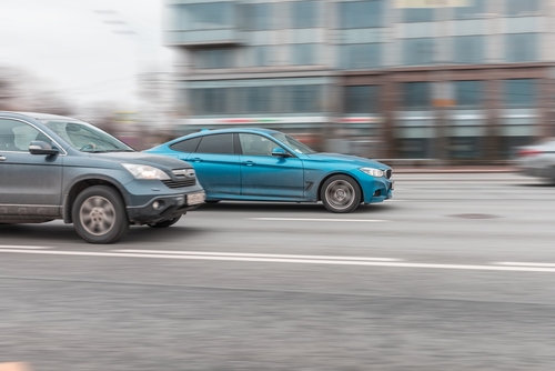 Cars speeding side by side on a busy roadway, illustrating alleged street racing cases handled by a Tampa highway racing lawyer.