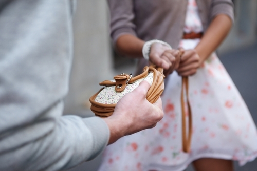 Person grabbing a woman's purse during a struggle, illustrating theft allegations handled by a Florida petit theft lawyer.