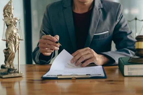 A lawyer reviewing legal documents at a desk with justice symbols nearby, illustrating cases handled with the support of a Tampa Orders of Protection Lawyer.