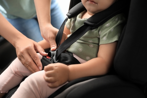 Florida DUI with child passenger lawyer represented through an adult securing a young child in a car seat, emphasizing child endangerment concerns.