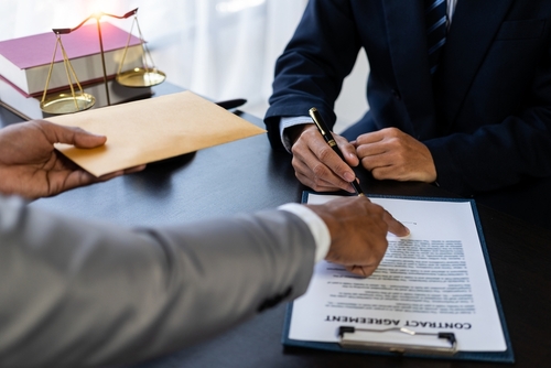 Tampa forgery lawyer illustrated through an attorney reviewing and signing documents as an envelope is exchanged, reflecting alleged document falsification.