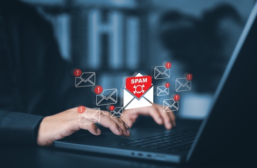 Tampa mail fraud lawyer represented through a person typing on a laptop with digital spam and alert icons, symbolizing federal mail fraud investigations.