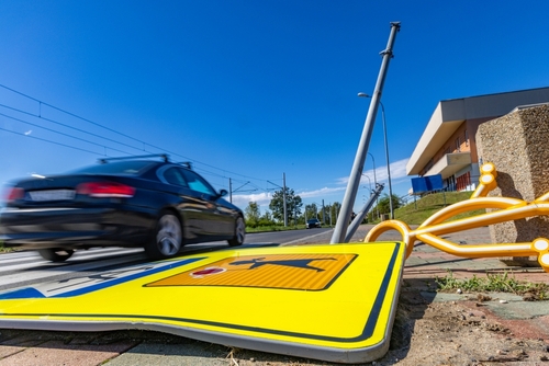 A car speeding past a damaged street sign and broken pole, depicting the aftermath of a collision handled by a Tampa hit and run defense lawyer.