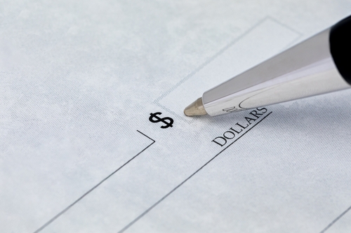 Pen hovering over a blank check’s dollar amount field, symbolizing allegations involving writing or passing worthless checks in Florida.