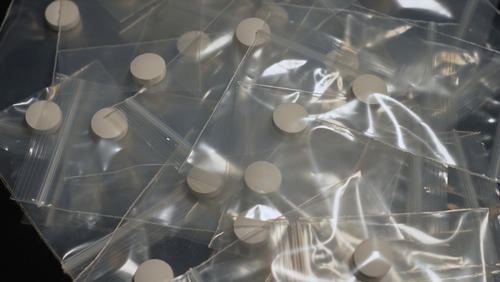 Small plastic bags filled with white tablets arranged on a dark surface, representing cases handled with the support of a Tampa Drug Cultivation & Manufacturing Defense Lawyer.