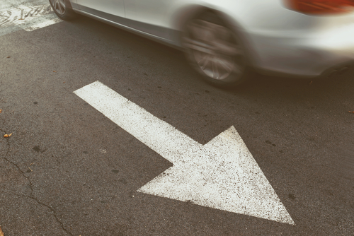 Car driving over a painted lane direction arrow, depicting violations handled for an improper lane change ticket in Tampa.