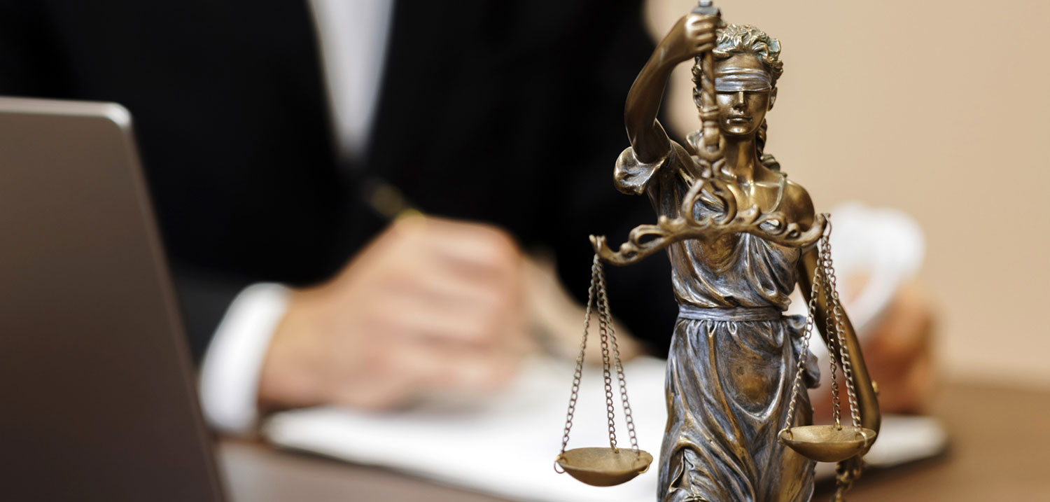 A defense attorney reviewing case files at a desk beside a Lady Justice statue, illustrating legal preparation after being accused of a drug crime in Tampa, Florida.