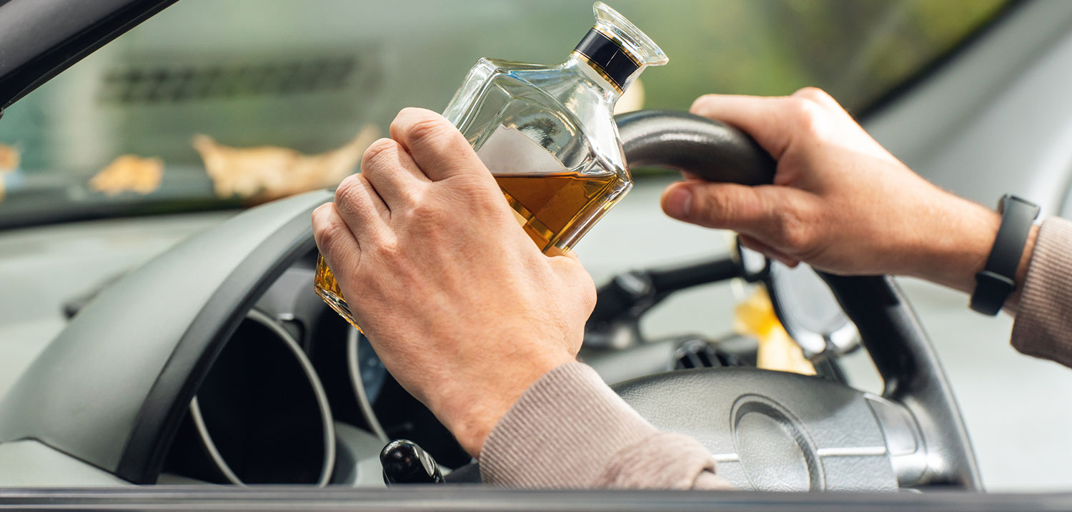 Driver holding an alcoholic drink behind the wheel, illustrating impaired driving risks connected to Florida Trent’s Law and DUI enforcement.